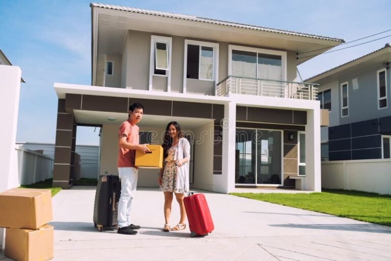 casal feliz com malas na frente de casa