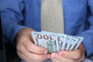 maos segurando dinheiro em escritorio formal