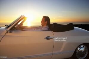 pessoa dirigindo carro sorridente ao por do sol