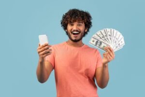 pessoa feliz olhando para celular comemorando dinheiro