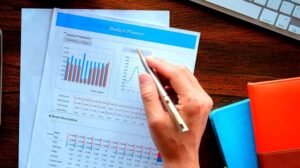 pessoa preenchendo planilha financeira com moedas