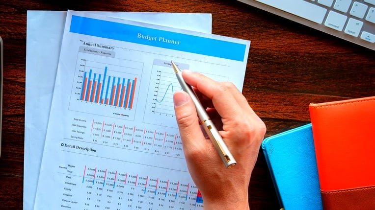 pessoa preenchendo planilha financeira com moedas