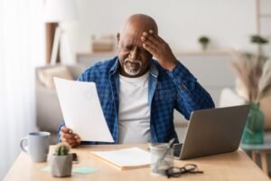 pessoa refletindo sobre documentos financeiros em mesa