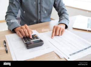 pessoa usando calculadora com documentos de trabalho