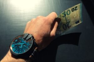 relogio ao lado de mao recebendo dinheiro