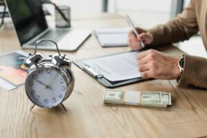 relogio e folhas de ponto sobre mesa